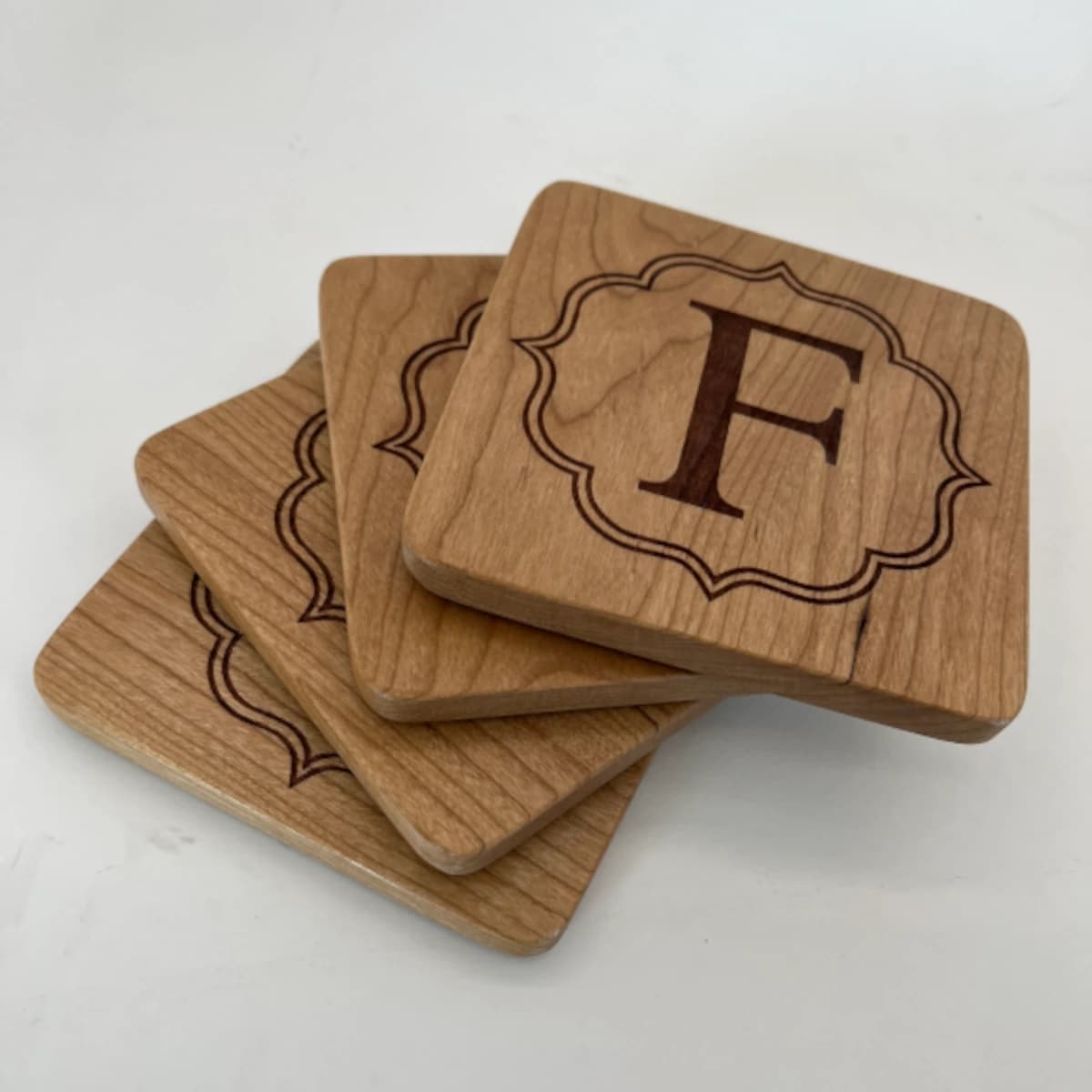 Set of 4 wooden coasters with a family initial laser-engraved on it.