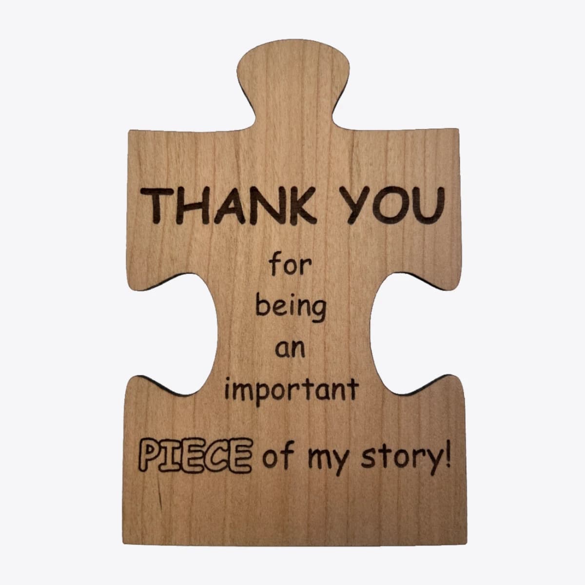 A wooden card in the shape of a puzzle piece that is laser engraved with text that says thank you for being an important piece of my story.