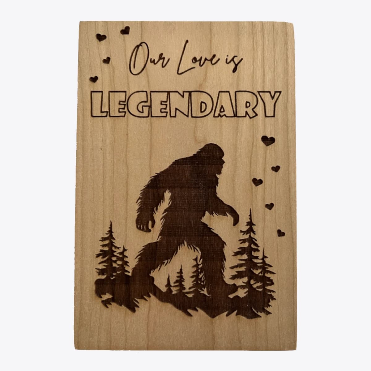 A wooden card that is laser engraved with an image of bigfoot and text that says our love is legendary.